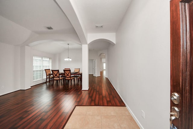 interior space featuring a chandelier, arched walkways, visible vents, and wood finished floors