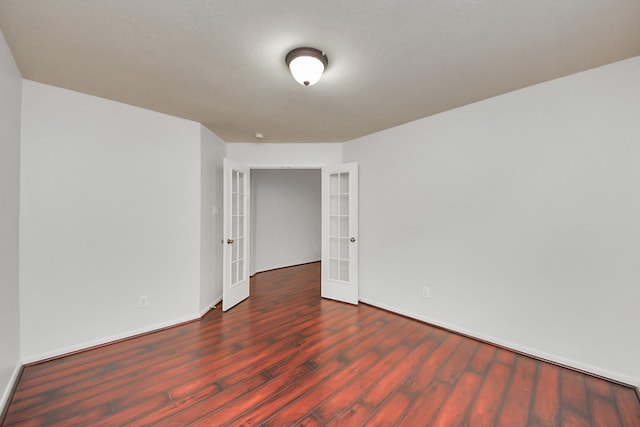 unfurnished room with french doors, dark wood finished floors, and baseboards