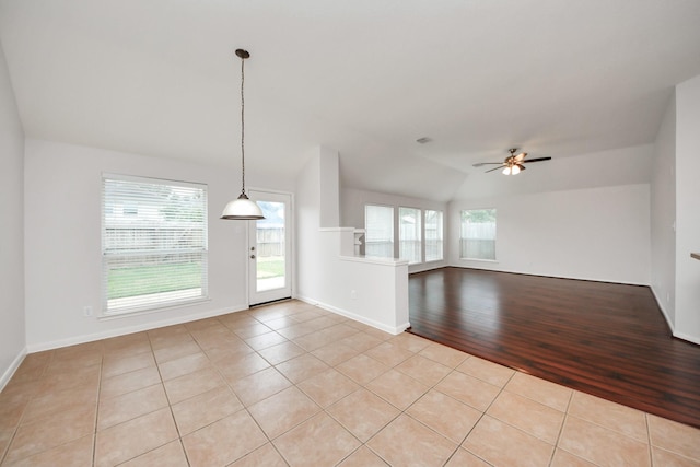 interior space with light tile patterned floors, ceiling fan, vaulted ceiling, and baseboards