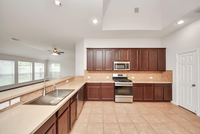 kitchen with a sink, stainless steel appliances, light countertops, backsplash, and light tile patterned flooring