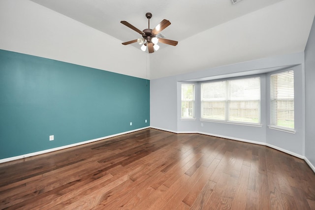 unfurnished room with vaulted ceiling, ceiling fan, wood finished floors, and baseboards