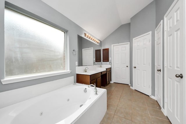 bathroom featuring lofted ceiling, tile patterned flooring, a sink, a jetted tub, and double vanity