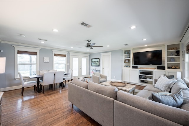 living room with french doors, hardwood / wood-style flooring, built in shelves, ceiling fan, and crown molding