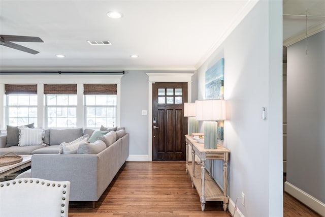 living room featuring hardwood / wood-style floors, ceiling fan, and crown molding