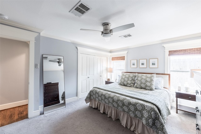 carpeted bedroom with ceiling fan, a closet, and crown molding