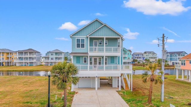 view of front of house with a garage, a water view, a balcony, and a front lawn