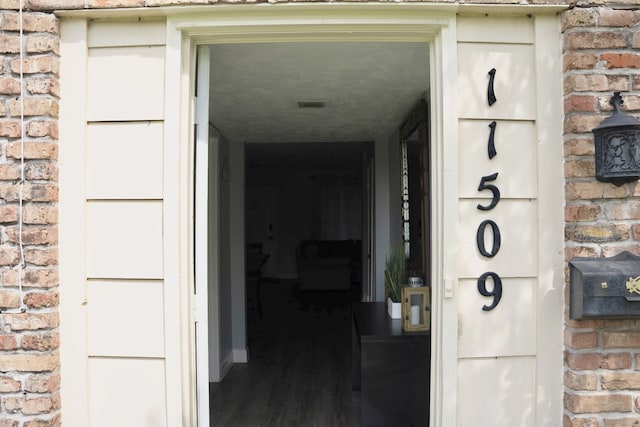 view of exterior entry with brick siding and visible vents