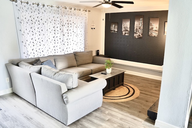 living room featuring baseboards, a ceiling fan, and wood finished floors