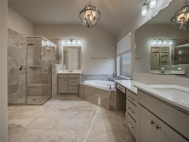 full bathroom with a garden tub, two vanities, vaulted ceiling, a stall shower, and an inviting chandelier