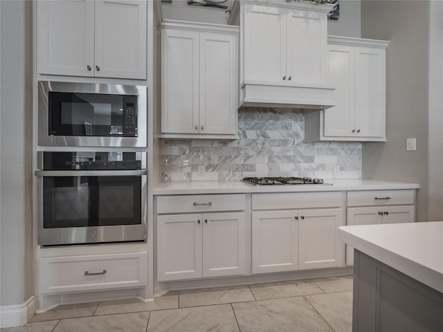 kitchen featuring stainless steel gas cooktop, custom range hood, light countertops, white cabinets, and built in microwave