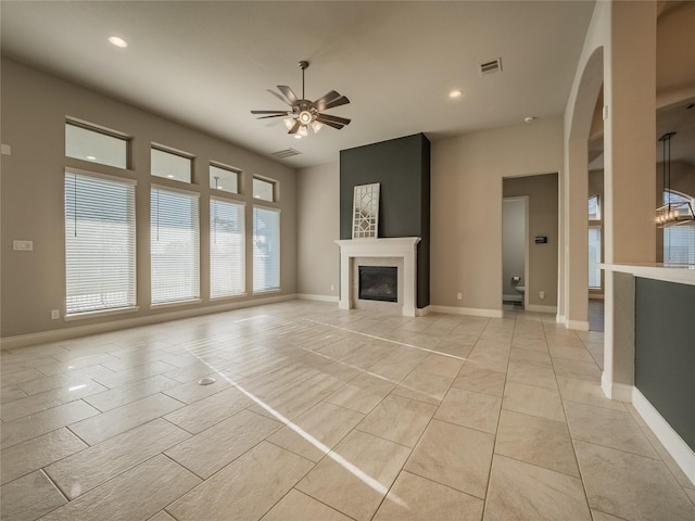 unfurnished living room with baseboards, visible vents, a ceiling fan, a glass covered fireplace, and light tile patterned flooring