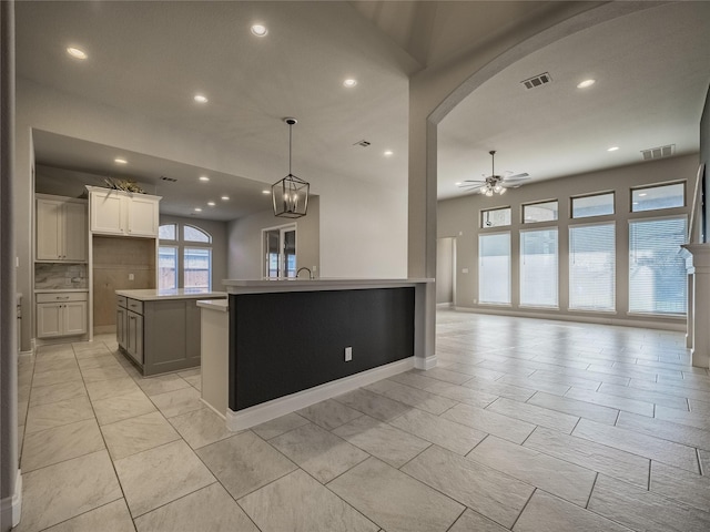 kitchen featuring open floor plan, light countertops, visible vents, and a center island with sink