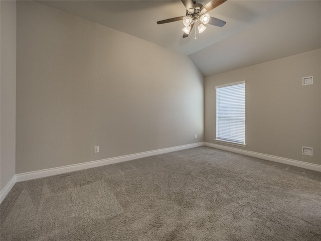 carpeted spare room with baseboards, vaulted ceiling, and a ceiling fan