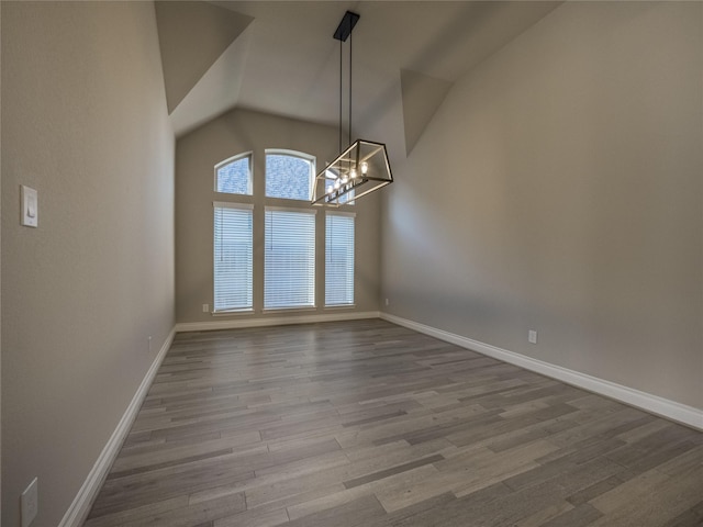 unfurnished dining area with high vaulted ceiling, baseboards, a chandelier, and wood finished floors