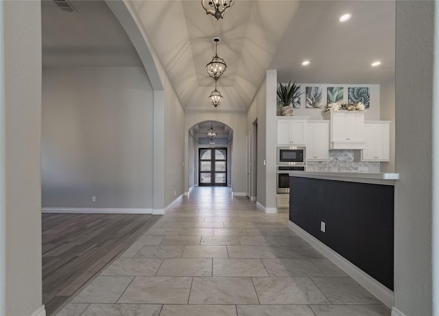 entryway with arched walkways, french doors, visible vents, a chandelier, and baseboards