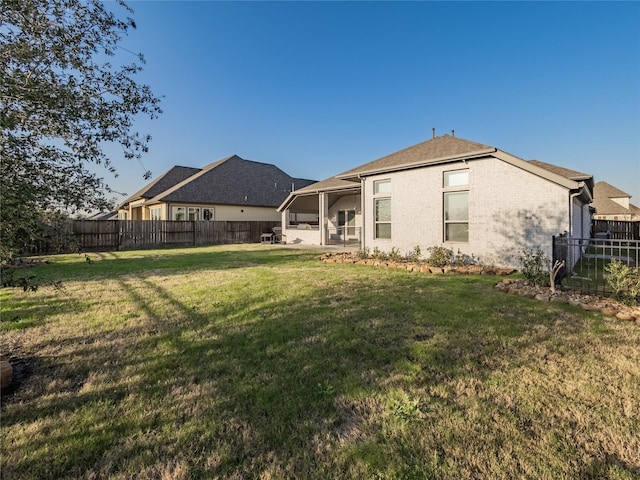 back of property with a fenced backyard, a lawn, and brick siding