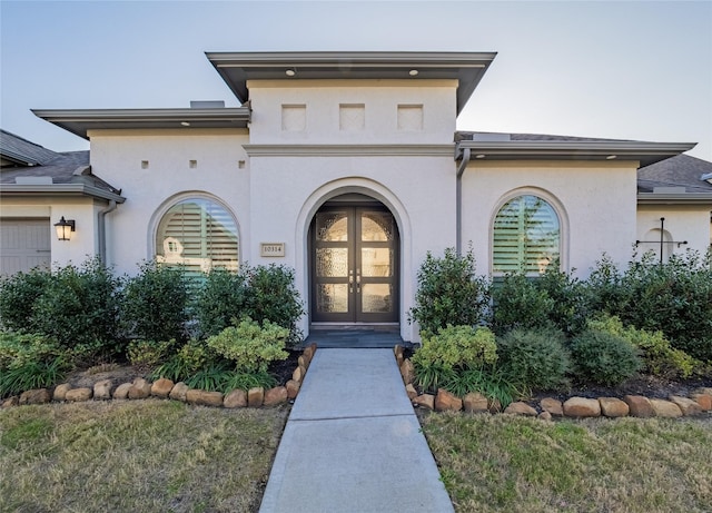 doorway to property with french doors, a lawn, and stucco siding