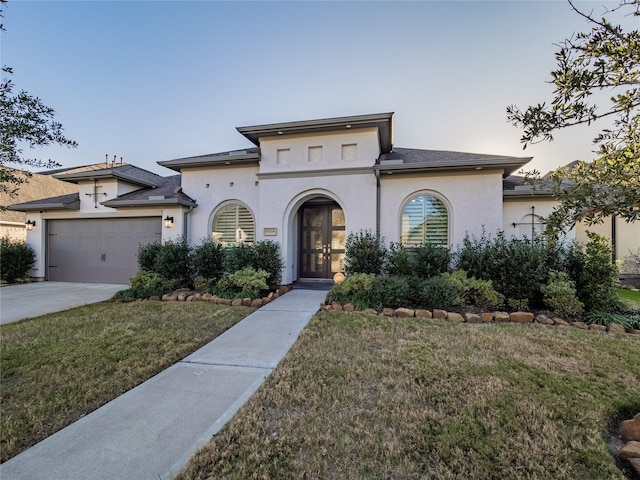 mediterranean / spanish-style house with a garage, concrete driveway, a front yard, and stucco siding