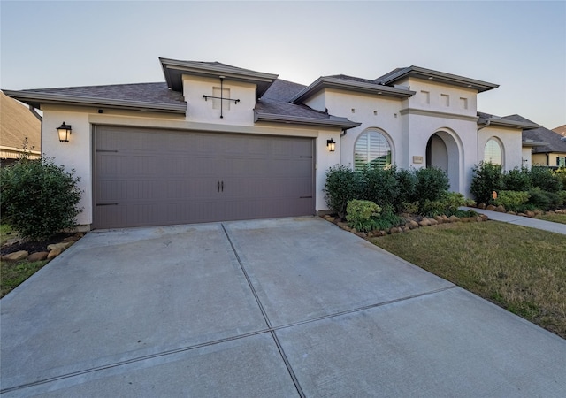 view of front facade with a garage, a front yard, concrete driveway, and stucco siding