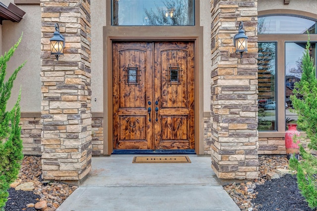 entrance to property featuring stone siding and stucco siding