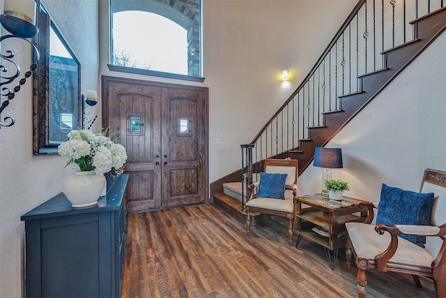 foyer entrance featuring stairway, dark wood-style flooring, and a high ceiling