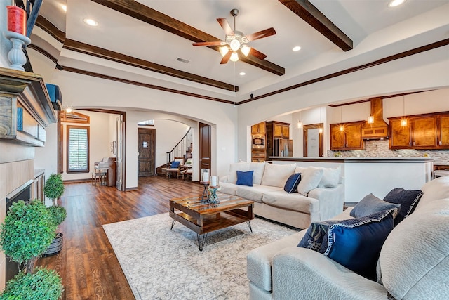 living area featuring dark wood-type flooring, visible vents, beamed ceiling, a fireplace, and arched walkways