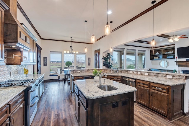 kitchen with light stone countertops, stainless steel appliances, a kitchen island with sink, and hanging light fixtures