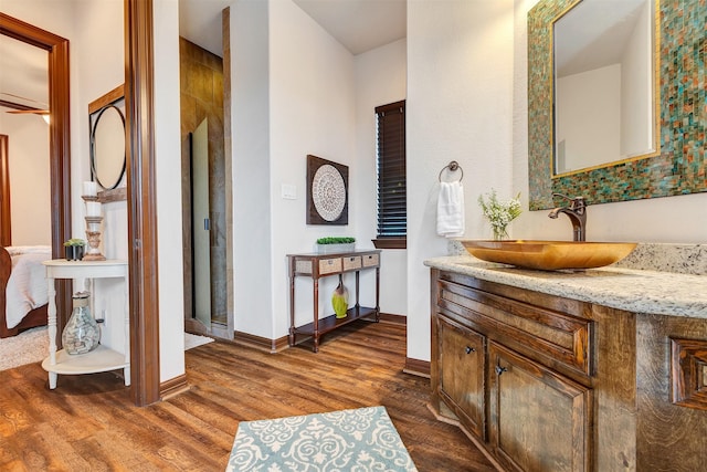 ensuite bathroom with baseboards, ensuite bathroom, wood finished floors, and vanity