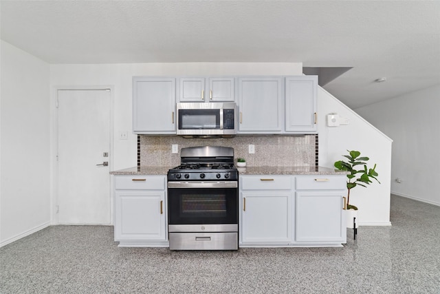 kitchen with stainless steel appliances, backsplash, white cabinetry, and light stone countertops