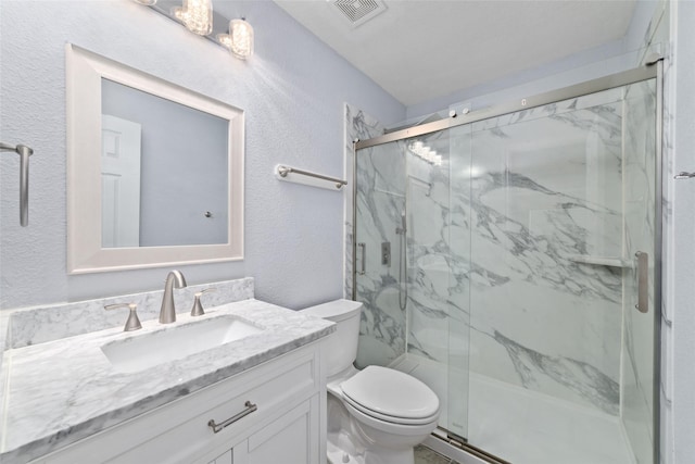 bathroom with toilet, vanity, and a shower with shower door