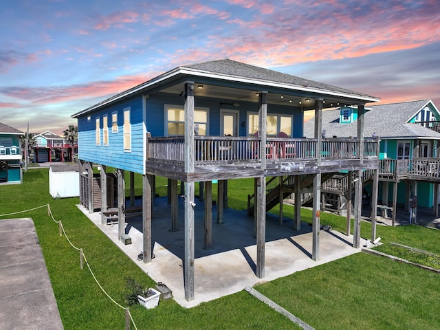 back house at dusk featuring a patio area, a carport, and a lawn