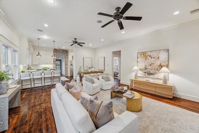 living room featuring ceiling fan, crown molding, and dark wood-type flooring