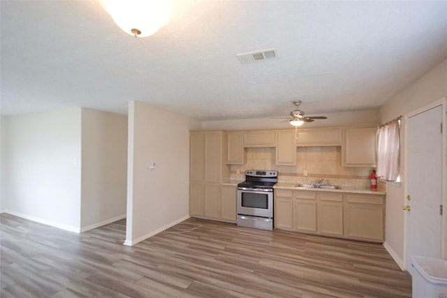 8030 Lawler St, Houston, TX 77051 - kitchen featuring ceiling fan, light wood-type flooring, stainless steel electric range oven, tasteful backsplash, and sink