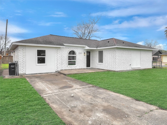 view of front of house featuring a patio area, a front lawn, a shingled roof, and brick siding