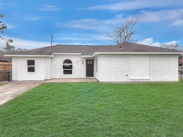 view of front of house featuring brick siding, a shingled roof, a front yard, and fence