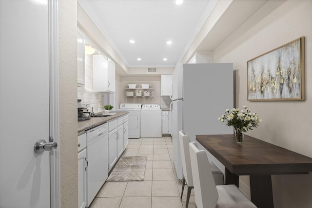 kitchen with light tile patterned flooring, white cabinetry, white appliances, ornamental molding, and sink