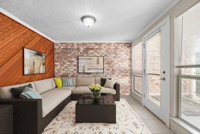 living room featuring brick wall, ornamental molding, wood walls, light tile patterned flooring, and a textured ceiling