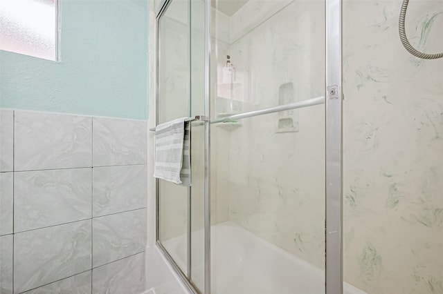bathroom featuring combined bath / shower with glass door