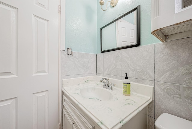 bathroom featuring toilet, tile walls, and vanity