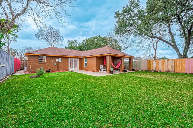 back of house featuring a lawn, french doors, and a patio area