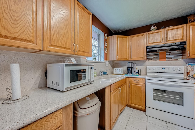 kitchen featuring sink, range hood, light stone countertops, light tile patterned floors, and white appliances