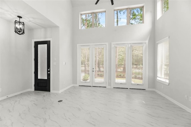 entrance foyer featuring baseboards, marble finish floor, and a towering ceiling