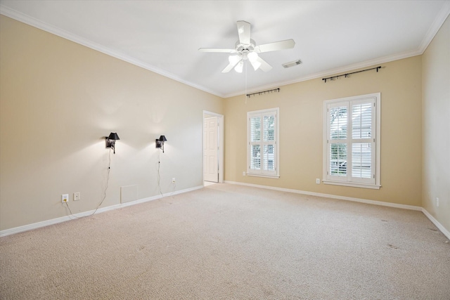 empty room featuring light carpet, a ceiling fan, baseboards, visible vents, and crown molding