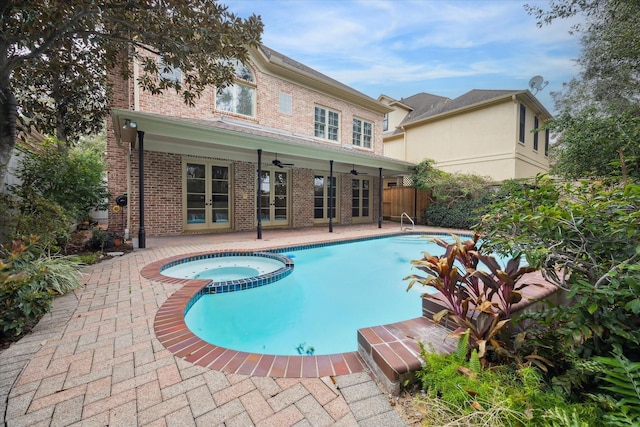 view of swimming pool with ceiling fan, fence, a pool with connected hot tub, and a patio