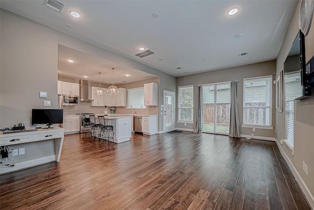 living area with visible vents and wood finished floors