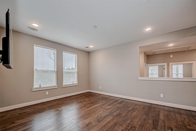 empty room featuring recessed lighting, visible vents, attic access, wood finished floors, and baseboards