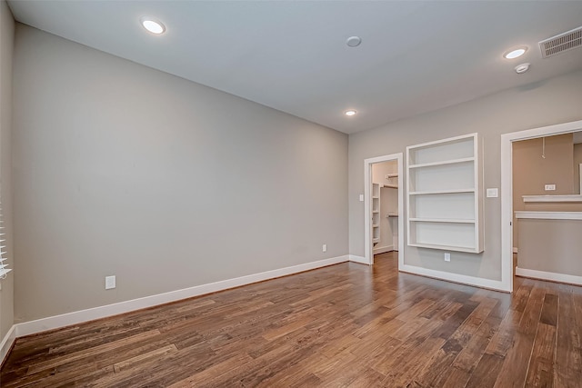 unfurnished bedroom with recessed lighting, wood finished floors, visible vents, baseboards, and a spacious closet