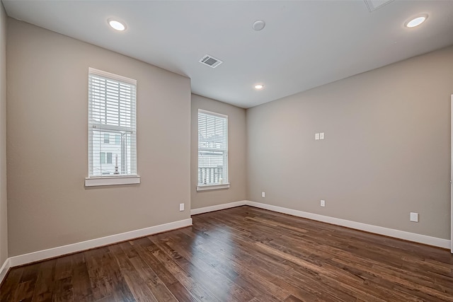 empty room featuring dark wood-type flooring, recessed lighting, visible vents, and baseboards