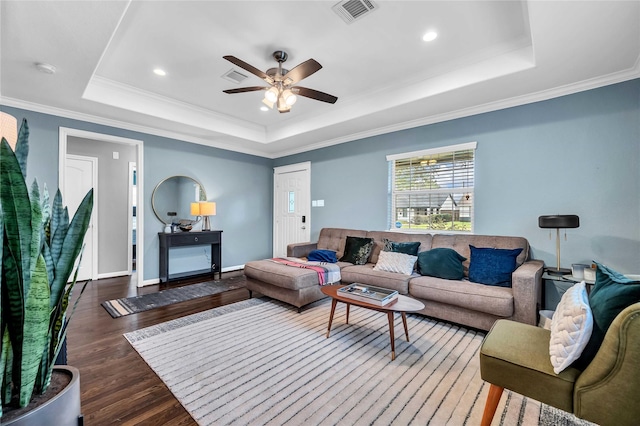 living room featuring a tray ceiling, crown molding, ceiling fan, and dark hardwood / wood-style flooring