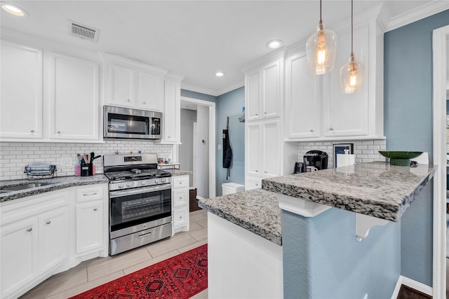 kitchen with stainless steel appliances, white cabinets, ornamental molding, and decorative light fixtures